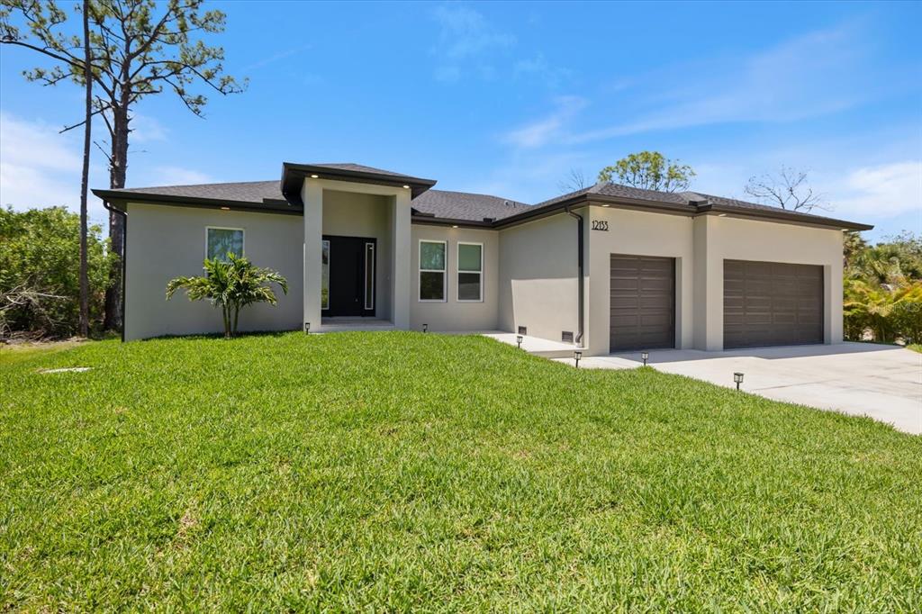 A single-story house with a gray exterior, two garage doors, and a front lawn — 12133 FEDERAL AVENUE, PORT CHARLOTTE, FL