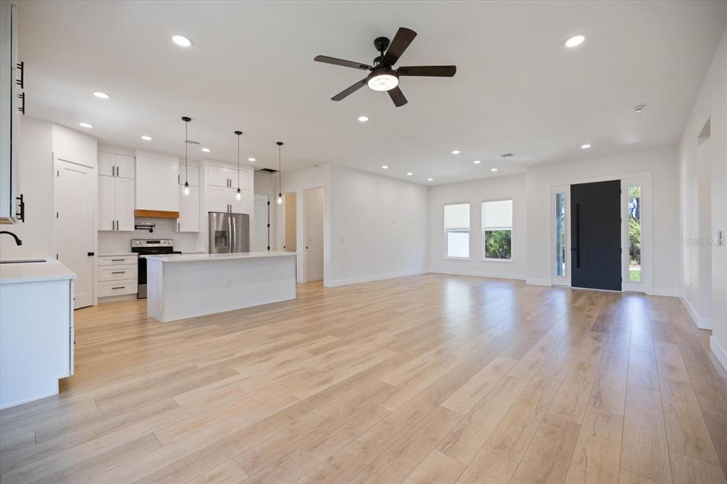 An open-concept kitchen and living area features white cabinetry, a central island, and light wood flooring — 12133 FEDERAL AVENUE, PORT CHARLOTTE, FL
