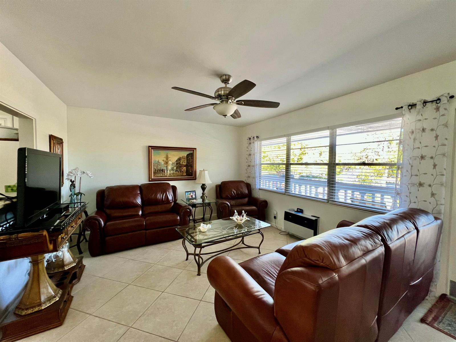 A living room features brown leather sofas, a glass coffee table, and large windows — 180 Tilford I, Deerfield Beach FL 33442, DEERFIELD BEACH, FL