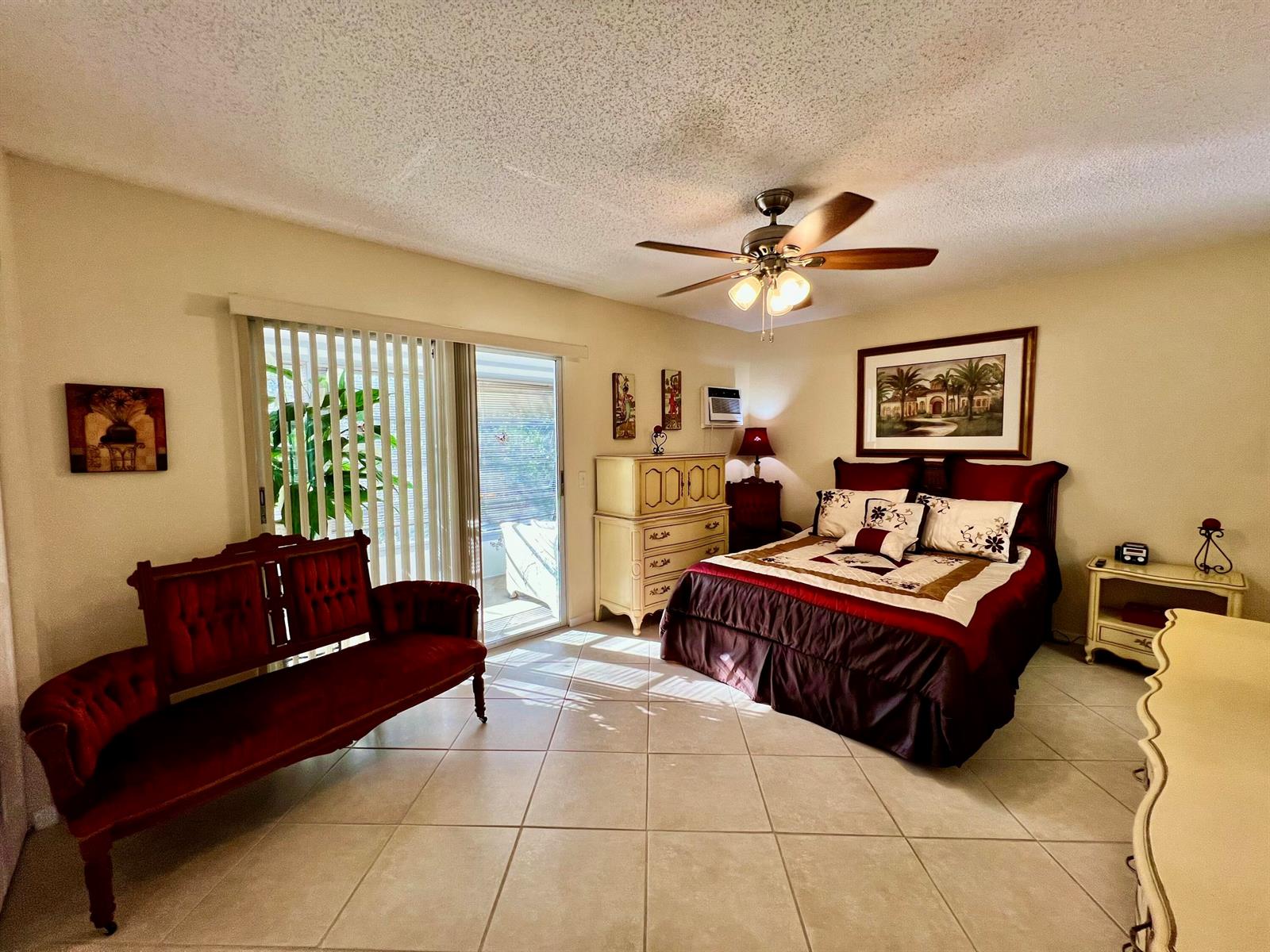 A bedroom with tile floors, a ceiling fan, a red settee, and a queen bed — 180 Tilford I, Deerfield Beach FL 33442, DEERFIELD BEACH, FL