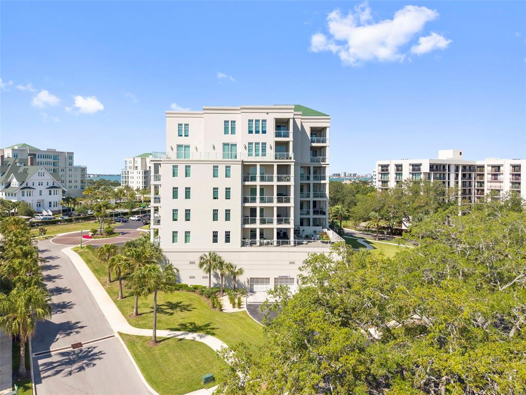 An exterior view of a multi-story residential building surrounded by trees and paved paths — 8 PALM TERRACE UNIT 201, CLEARWATER, FL