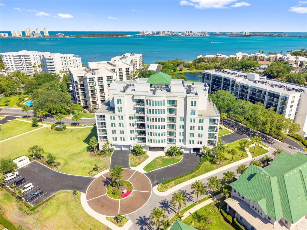 An aerial view shows a multi-story apartment building with a circular driveway and water views — 8 PALM TERRACE UNIT 201, CLEARWATER, FL