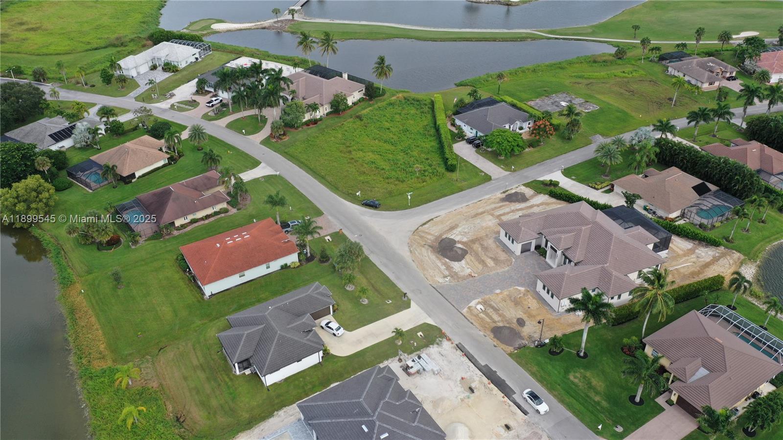 An aerial view shows a suburban neighborhood with houses, paved roads, and a small lake — 18018 Royal Hammock Blvd, Naples FL 34114, NAPLES, FL