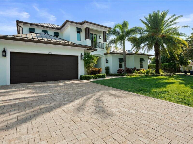 A two-story house with a paved driveway, a large garage, and palm trees — 205 Body Court, Jupiter FL 33477, JUPITER, FL