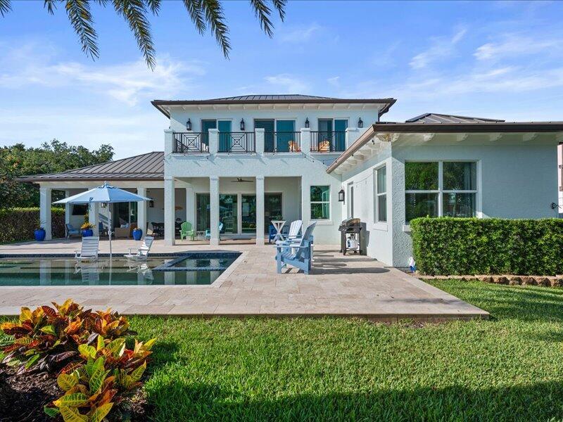 A two-story house features a swimming pool, patio, and balcony under a clear blue sky — 205 Body Court, Jupiter FL 33477, JUPITER, FL