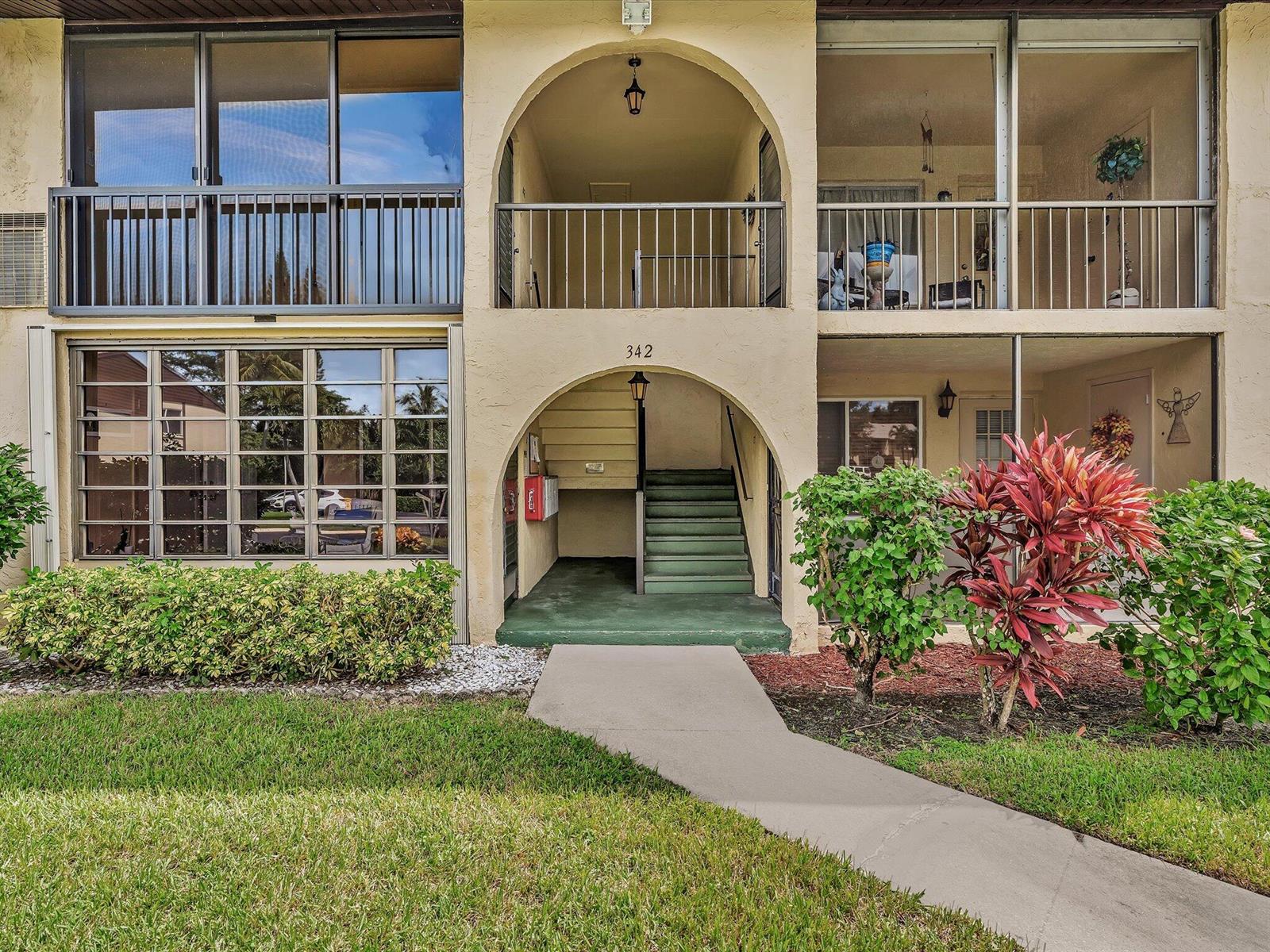 Exterior view of a two-story apartment building with arched entryways, balconies, and landscaped grounds — 342 Pine Ridge Circle # 2, FL 33463, FL
