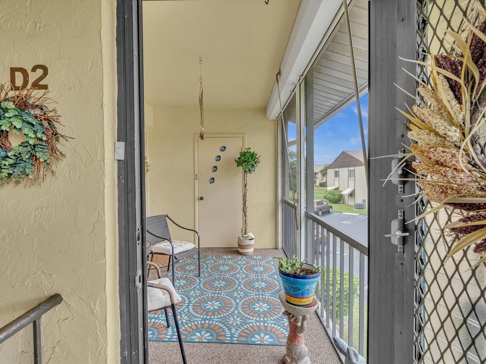 A screened-in balcony features a patterned rug, two chairs, a potted plant, and a door — 342 Pine Ridge Circle # 2, FL 33463, FL