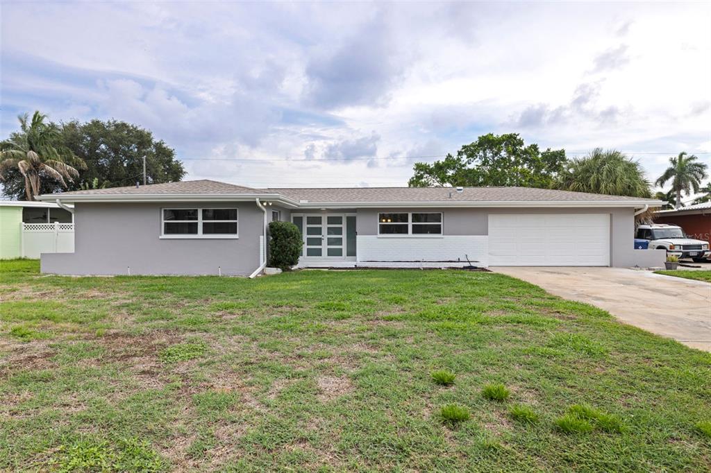 A single-story house with a gray exterior, white garage door, and a front lawn — 7073 S SHORE DRIVE S, ST PETERSBURG, FL