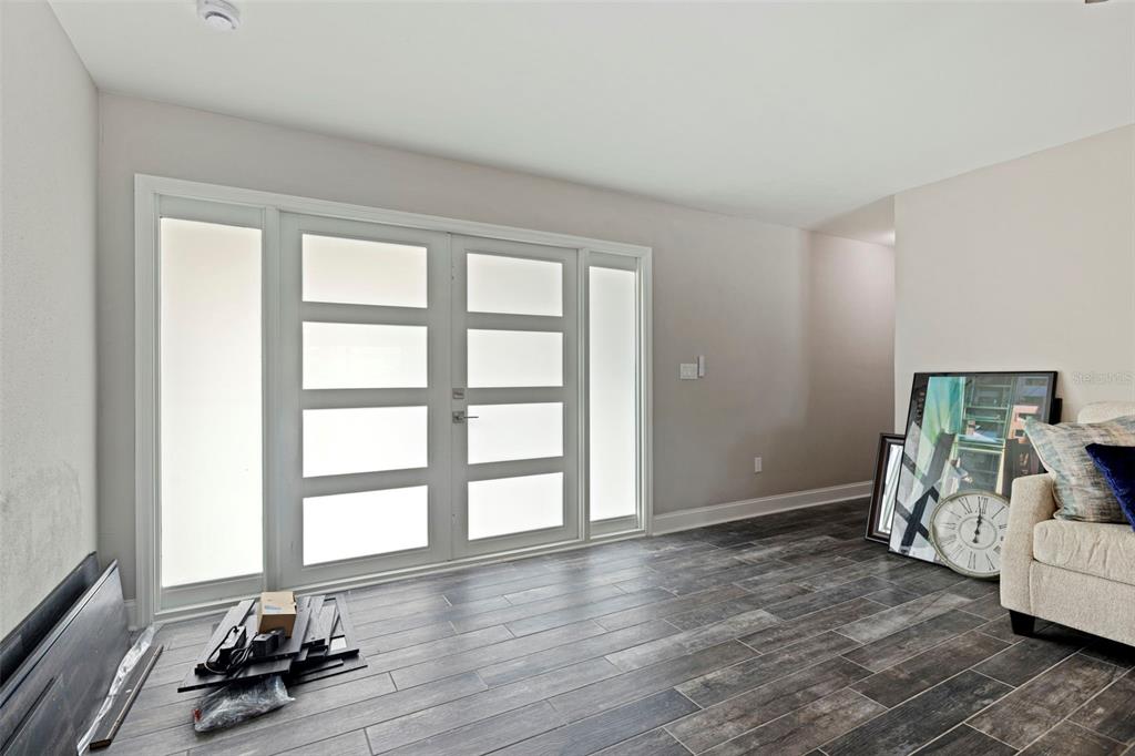 A room with dark wood-look tile flooring features a double front door with frosted glass panels — 7073 S SHORE DRIVE S, ST PETERSBURG, FL
