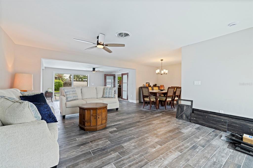 An open-concept living and dining area features wood-look tile flooring and a ceiling fan — 7073 S SHORE DRIVE S, ST PETERSBURG, FL