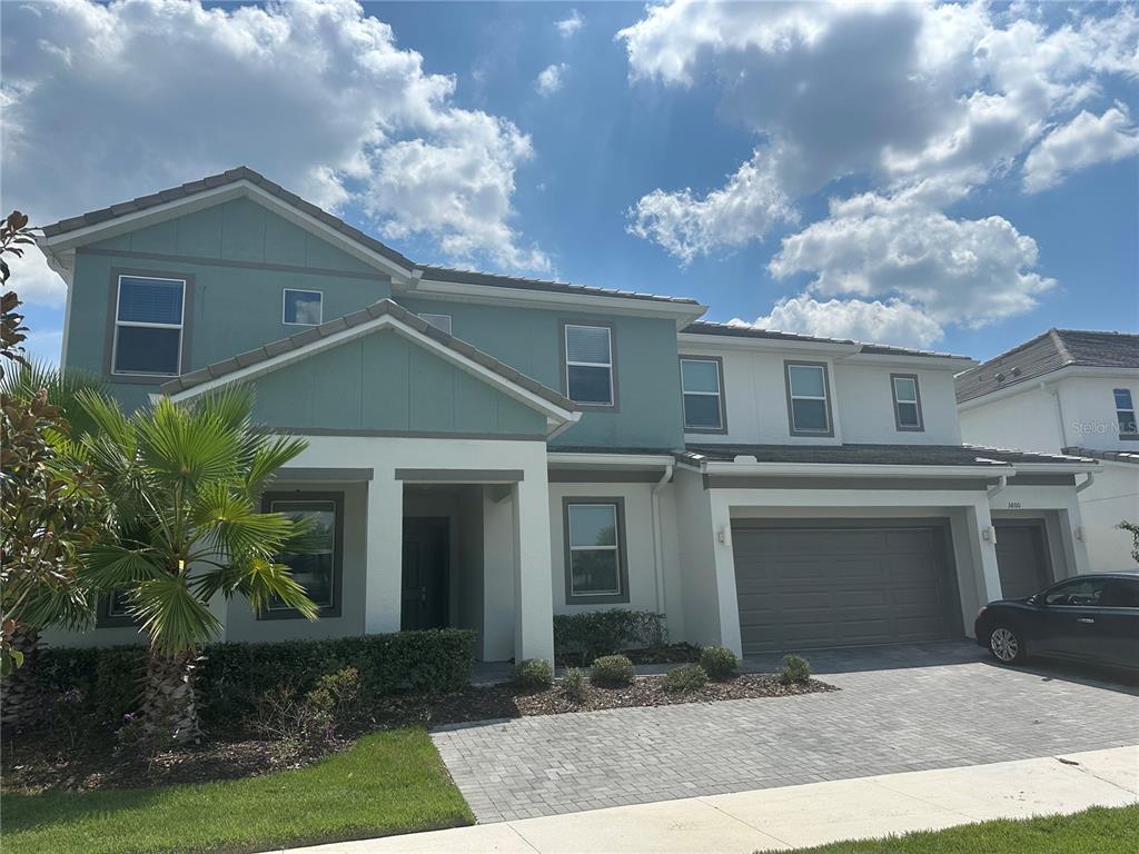 A two-story house with a teal and white exterior, a paved driveway, and a garage — 3800 SONOMA BOULEVARD, KISSIMMEE, FL
