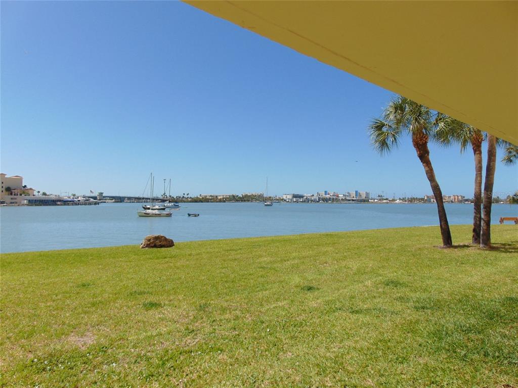 A grassy lawn overlooks a bay with sailboats and a distant city skyline — 4775 COVE CIRCLE N UNIT 104, ST PETERSBURG, FL