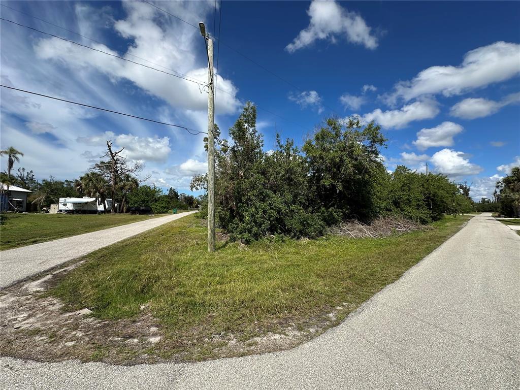 A corner lot with a utility pole and dense vegetation sits between two paved roads — 4315 GARDEN ROAD, PORT CHARLOTTE, FL