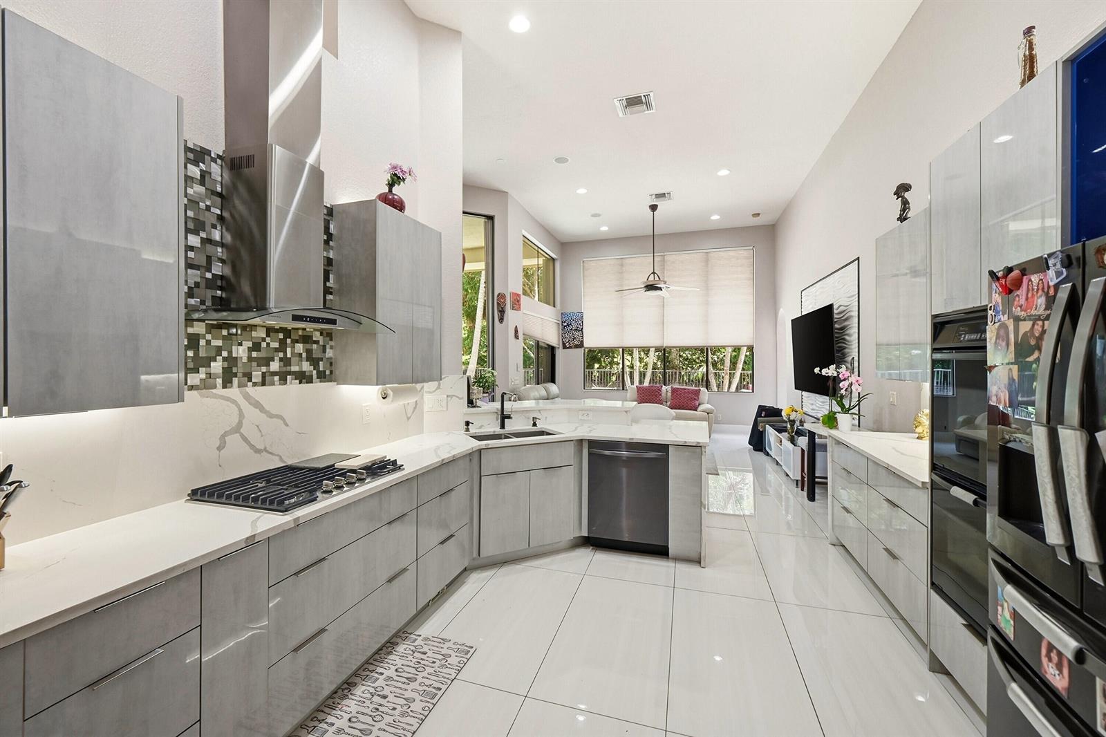 A modern kitchen features gray flat-panel cabinets, white marble-look countertops, and stainless steel appliances — 10340 Trianon Place, Wellington FL 33449, WELLINGTON, FL