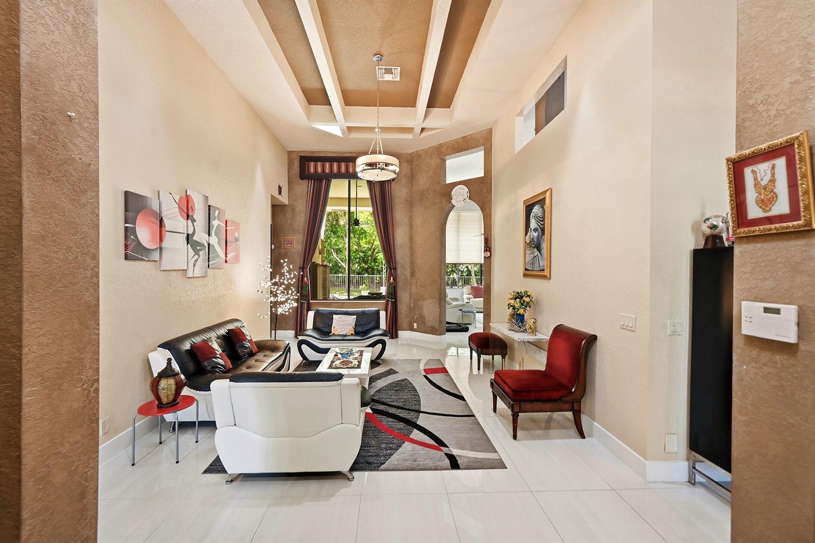 A living room with high ceilings, tile floors, modern furniture, and a large area rug — 10340 Trianon Place, Wellington FL 33449, WELLINGTON, FL