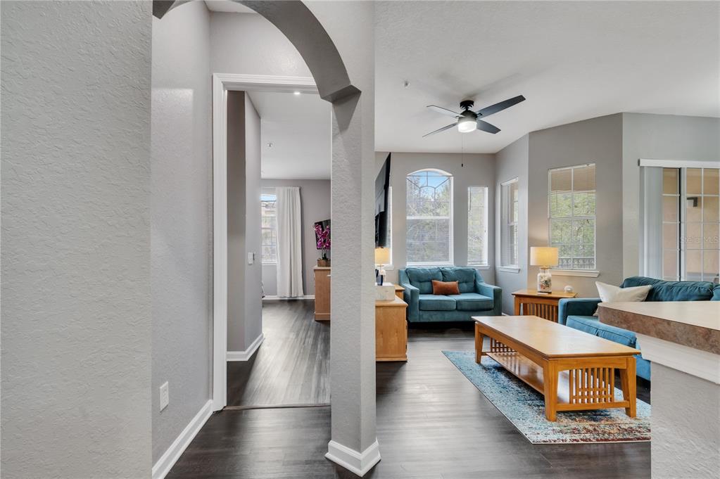 A living room with blue sofas and wood furniture connects to a hallway through an archway — 505 TERRACE RIDGE CIRCLE UNIT 505, DAVENPORT, FL