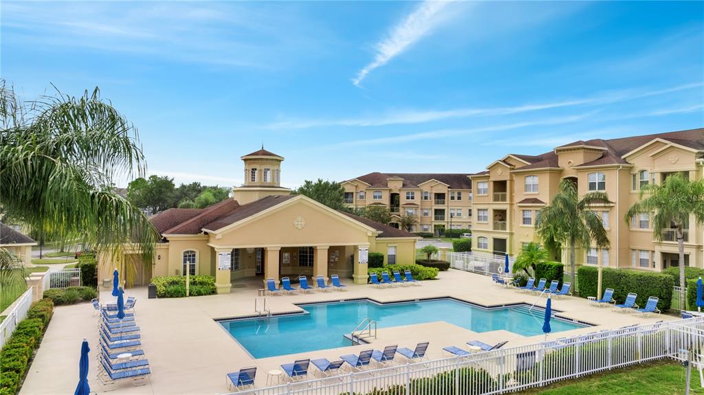 An outdoor swimming pool surrounded by lounge chairs and a clubhouse building at an apartment complex — 505 TERRACE RIDGE CIRCLE UNIT 505, DAVENPORT, FL