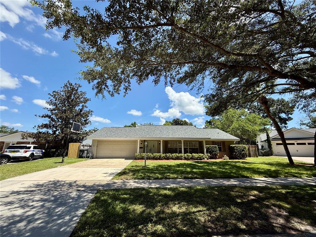 A single-story suburban house with a gray roof, beige siding, and a large front yard — 1625 TIOGA TRAIL, WINTER PARK, FL