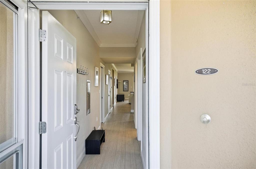 An open front door reveals a long hallway with light-colored tile flooring and white trim — 60 SURFVIEW DRIVE UNIT 122, PALM COAST, FL