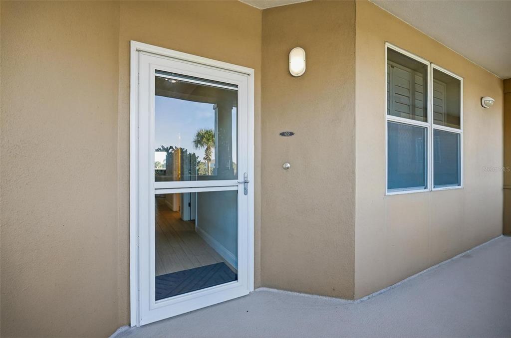 A white storm door leads into a tan-walled entryway with a window and light fixture — 60 SURFVIEW DRIVE UNIT 122, PALM COAST, FL