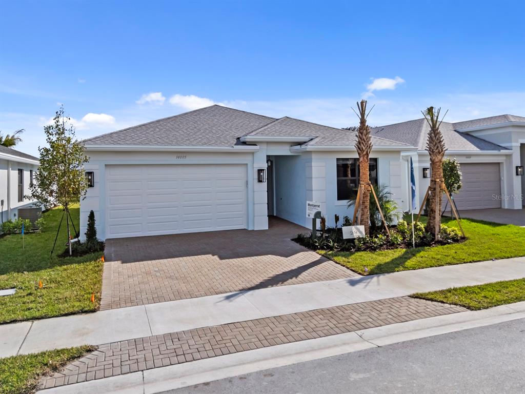 A single-story suburban house features a white exterior, a two-car garage, and a paved driveway — 14005 ALDERSGATE AVENUE, FORT MYERS, FL
