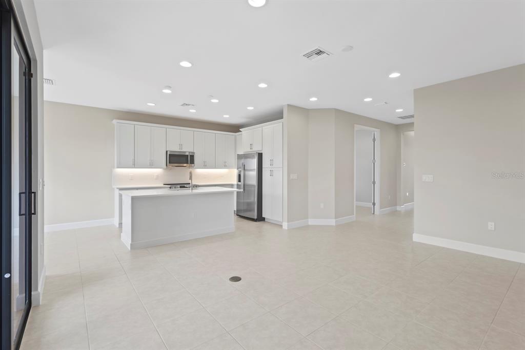 A modern kitchen with white cabinetry, stainless steel appliances, and a central island — 14005 ALDERSGATE AVENUE, FORT MYERS, FL