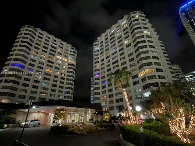 Two tall residential buildings stand illuminated at night above a landscaped entrance area — 999 Brickell Bay Drive # 1202, Miami FL 33131, MIAMI, FL