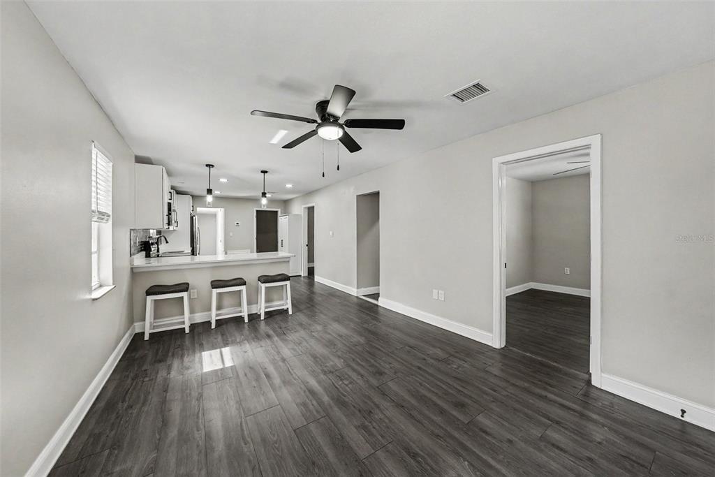 A kitchen with a breakfast bar and gray wood-look flooring opens into a living area — 1204 E CAYUGA STREET, TAMPA, FL