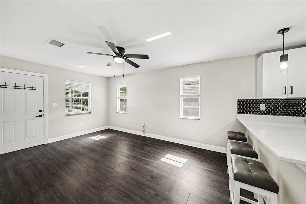 A room with dark wood-look flooring, a ceiling fan, and a kitchen breakfast bar — 1204 E CAYUGA STREET, TAMPA, FL