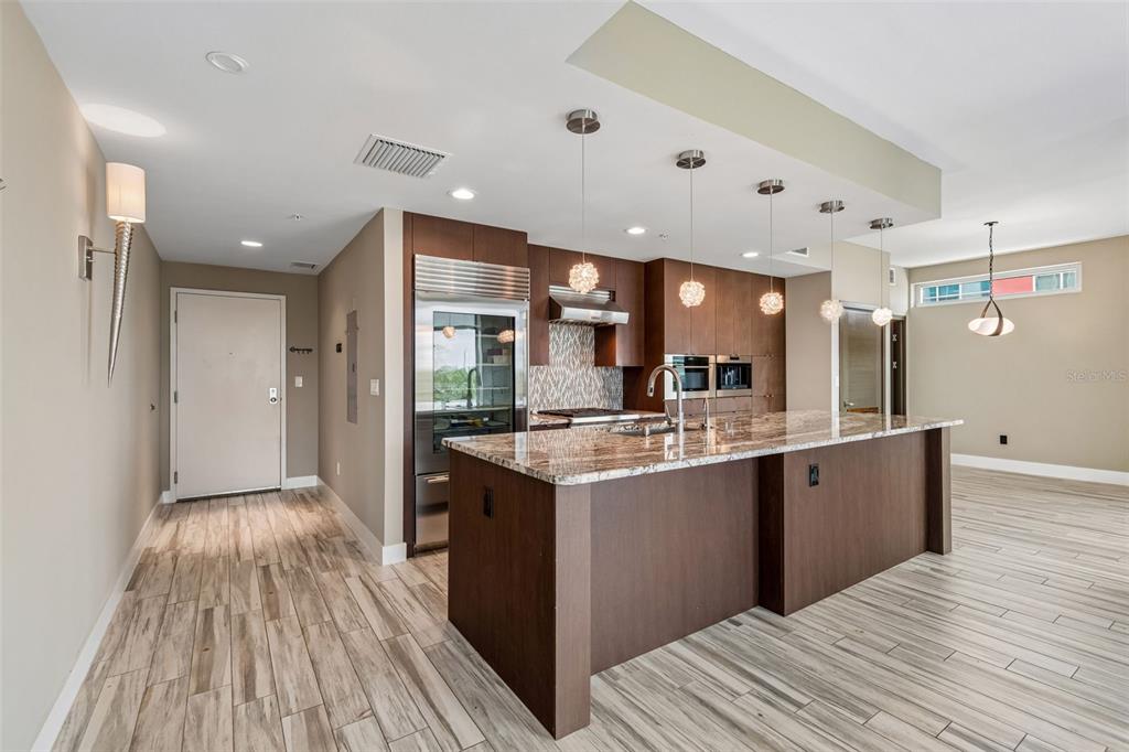 A modern kitchen features dark wood cabinetry, granite countertops, a large island, and tile flooring — 1120 E KENNEDY BOULEVARD W UNIT 1030, TAMPA, FL