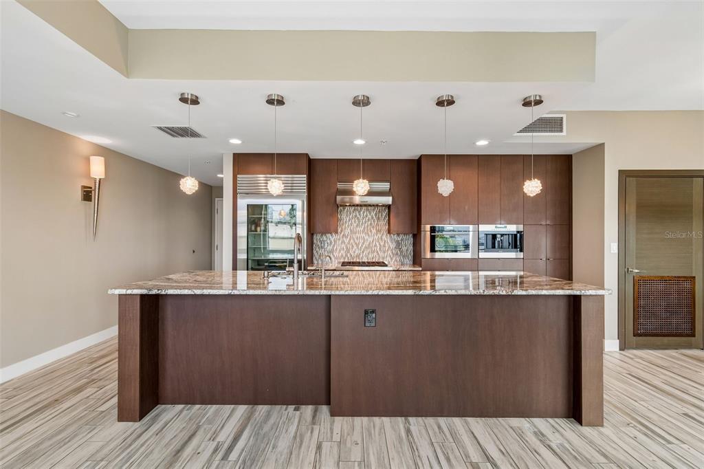 A modern kitchen features a large granite island, dark wood cabinetry, and stainless steel appliances — 1120 E KENNEDY BOULEVARD W UNIT 1030, TAMPA, FL