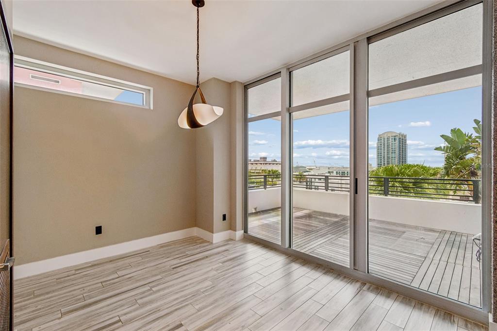 An empty room with wood-look tile flooring, a modern pendant light, and sliding glass doors — 1120 E KENNEDY BOULEVARD W UNIT 1030, TAMPA, FL