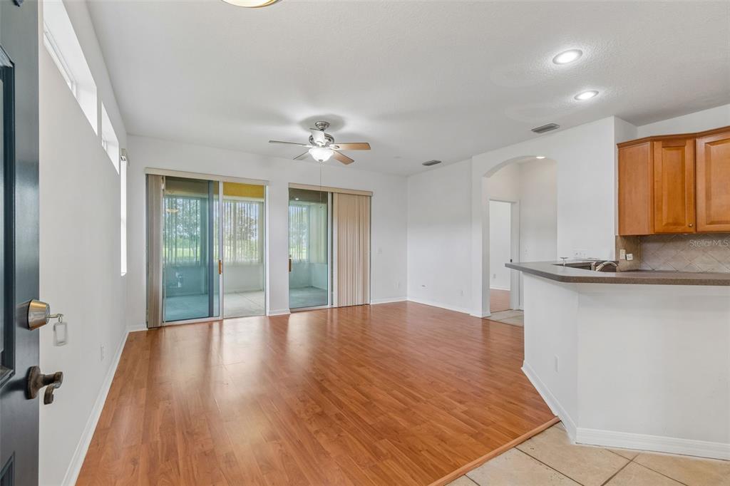 A living room with wood-look flooring, a ceiling fan, and sliding doors leading to a lanai — 1105 JAMESON GREENS DRIVE UNIT 1105, SUN CITY CENTER, FL