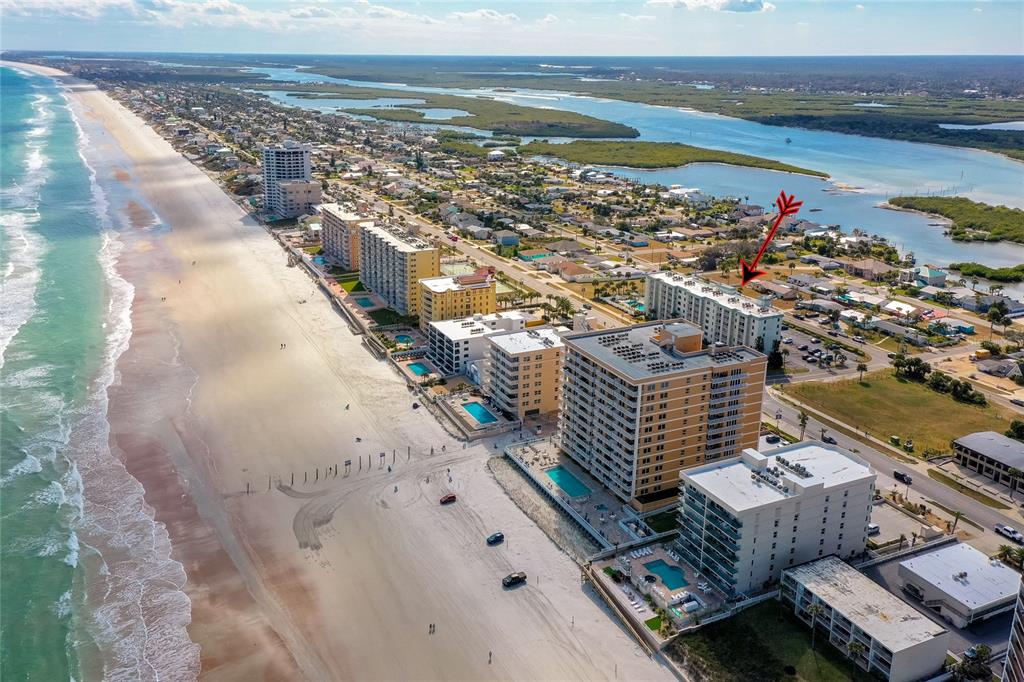 An aerial view shows several beachfront high-rise condominiums along a sandy coastline — 3800 S ATLANTIC AVENUE UNIT 207, DAYTONA BEACH, FL