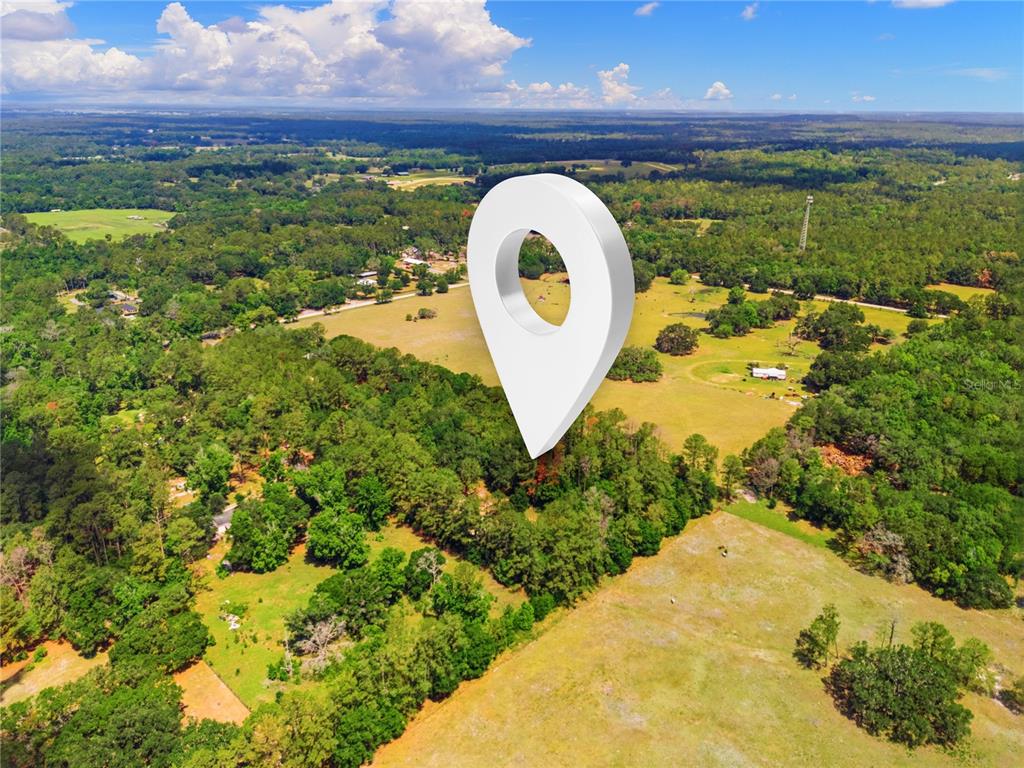 An aerial view shows a large, grassy rural lot surrounded by trees and forest — 1074 CULBREATH ROAD, BROOKSVILLE, FL