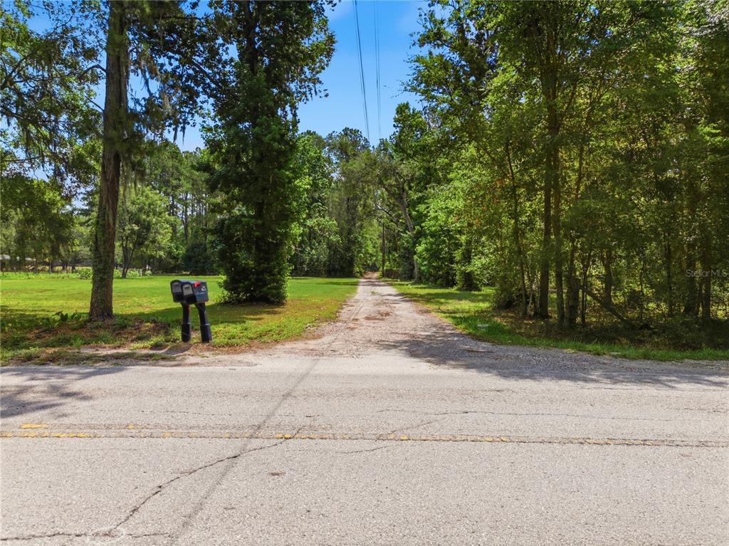 A gravel driveway leads from a paved road into a wooded, grassy lot — 1074 CULBREATH ROAD, BROOKSVILLE, FL
