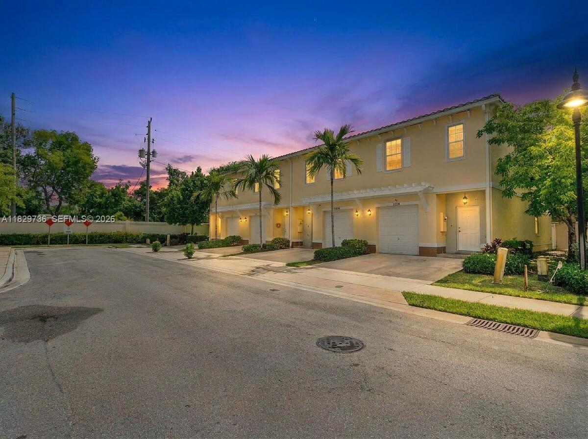 A row of two-story townhouses with garages and palm trees at dusk — 1128 NW 40th Ter, Lauderhill FL 33313, LAUDERHILL, FL