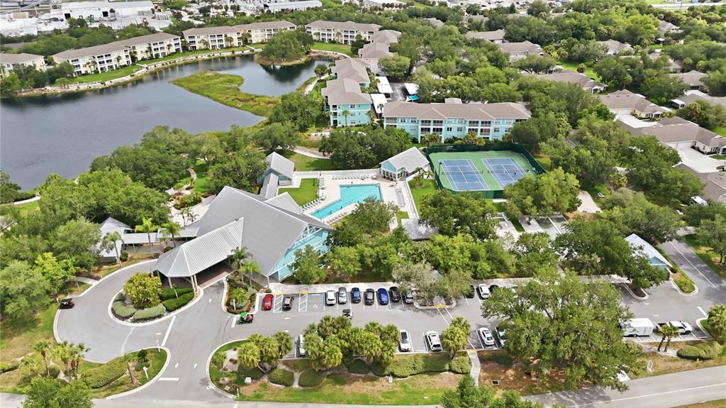 An aerial view shows a residential complex with a lake, swimming pool, and tennis courts — 19310 WATER OAK DRIVE UNIT 203, PORT CHARLOTTE, FL