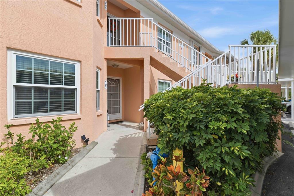 A peach-colored two-story apartment building with an exterior staircase and a concrete walkway — 19310 WATER OAK DRIVE UNIT 203, PORT CHARLOTTE, FL