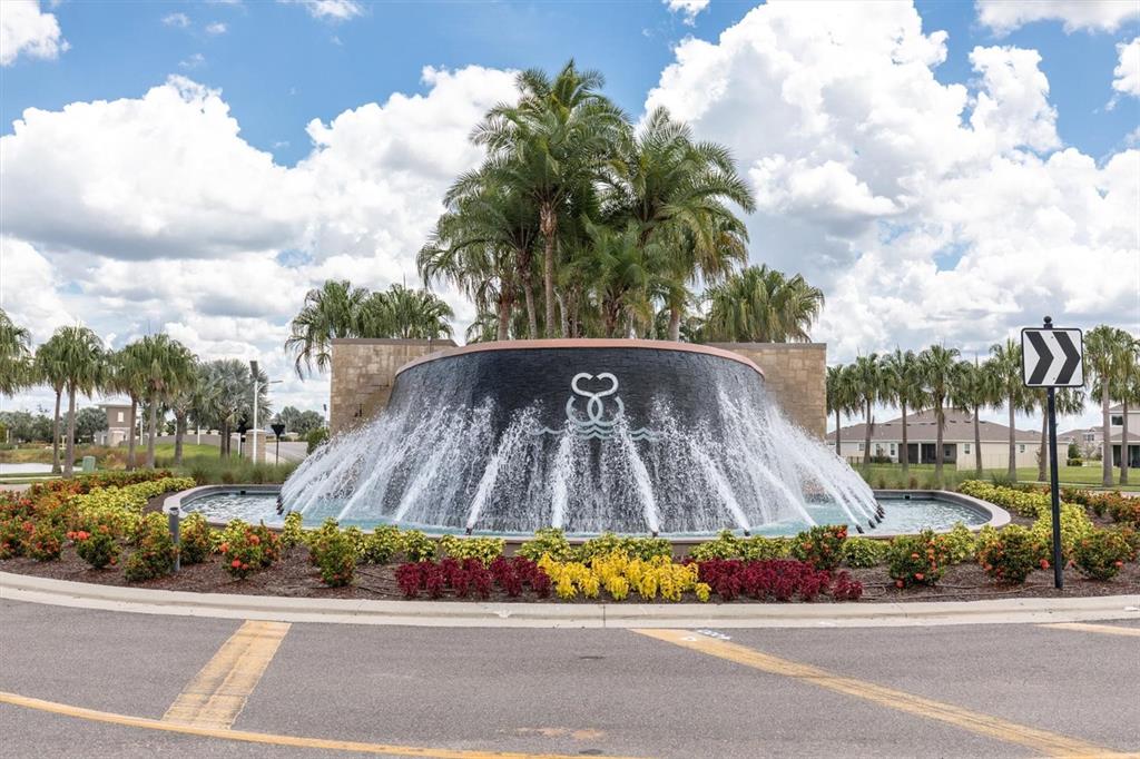 A large circular fountain with a stone wall and palm trees sits in a roundabout — 17070 OVAL RUM DRIVE, WIMAUMA, FL
