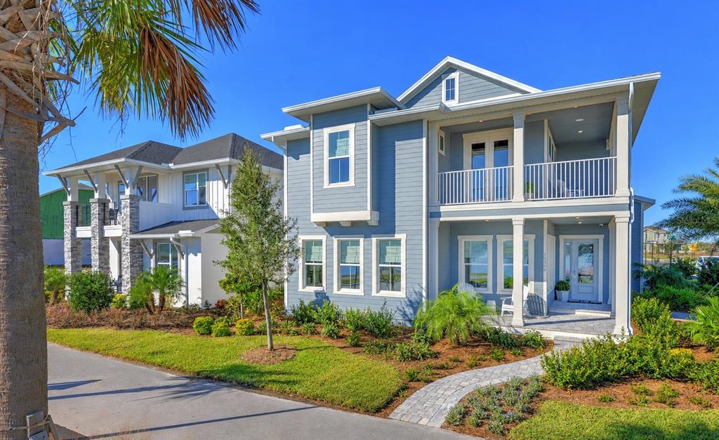 A two-story blue house with a front porch, balcony, and landscaped yard under a clear sky — 10504 PEARSON AVENUE, ORLANDO, FL