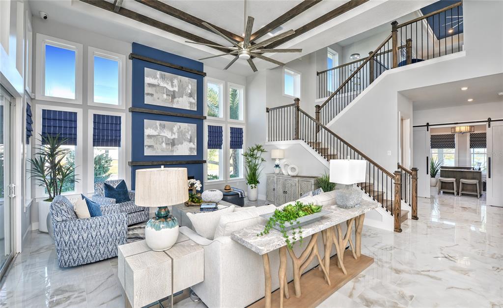 A bright living room features a blue accent wall, marble floors, and a grand staircase — 10504 PEARSON AVENUE, ORLANDO, FL