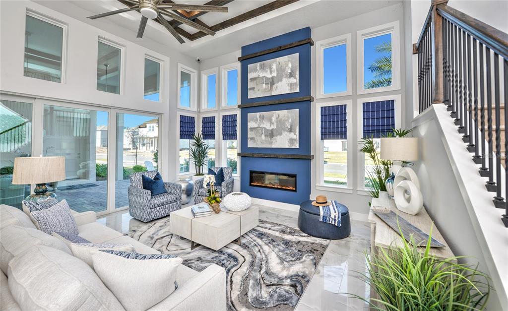 A modern living room features a blue fireplace wall, high ceilings, and large windows — 10504 PEARSON AVENUE, ORLANDO, FL