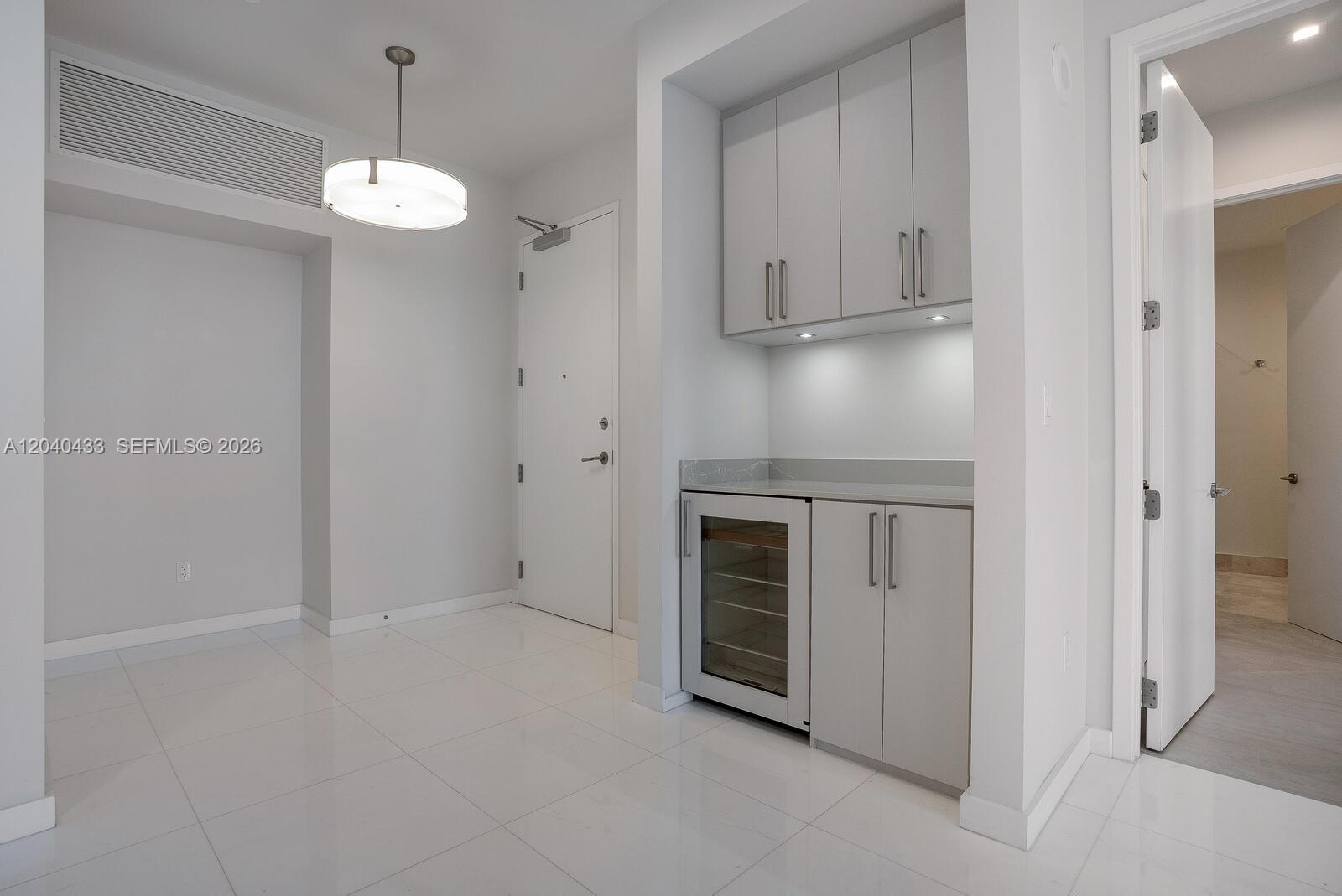 A modern, white-tiled room features a built-in wet bar with a wine cooler — 275 Giralda Ave # 6C, Coral Gables FL 33134, CORAL GABLES, FL