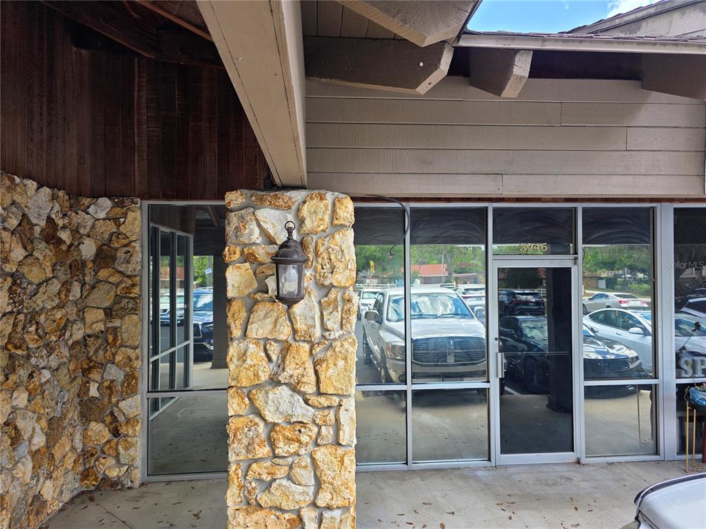 The exterior entrance features a stone pillar, glass storefront doors, and wood siding — 3946 LAKE PADGETT DRIVE, LAND O LAKES, FL