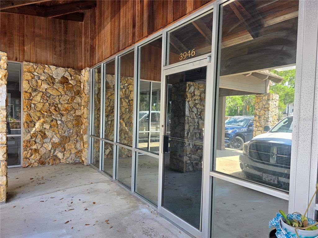 The exterior of a commercial building features a glass storefront with stone walls and wood — 3946 LAKE PADGETT DRIVE, LAND O LAKES, FL