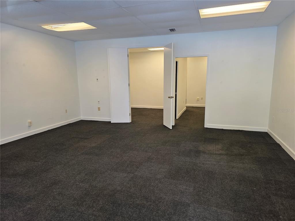 An empty office space features white walls, dark gray carpeting, and two open doorways — 3946 LAKE PADGETT DRIVE, LAND O LAKES, FL