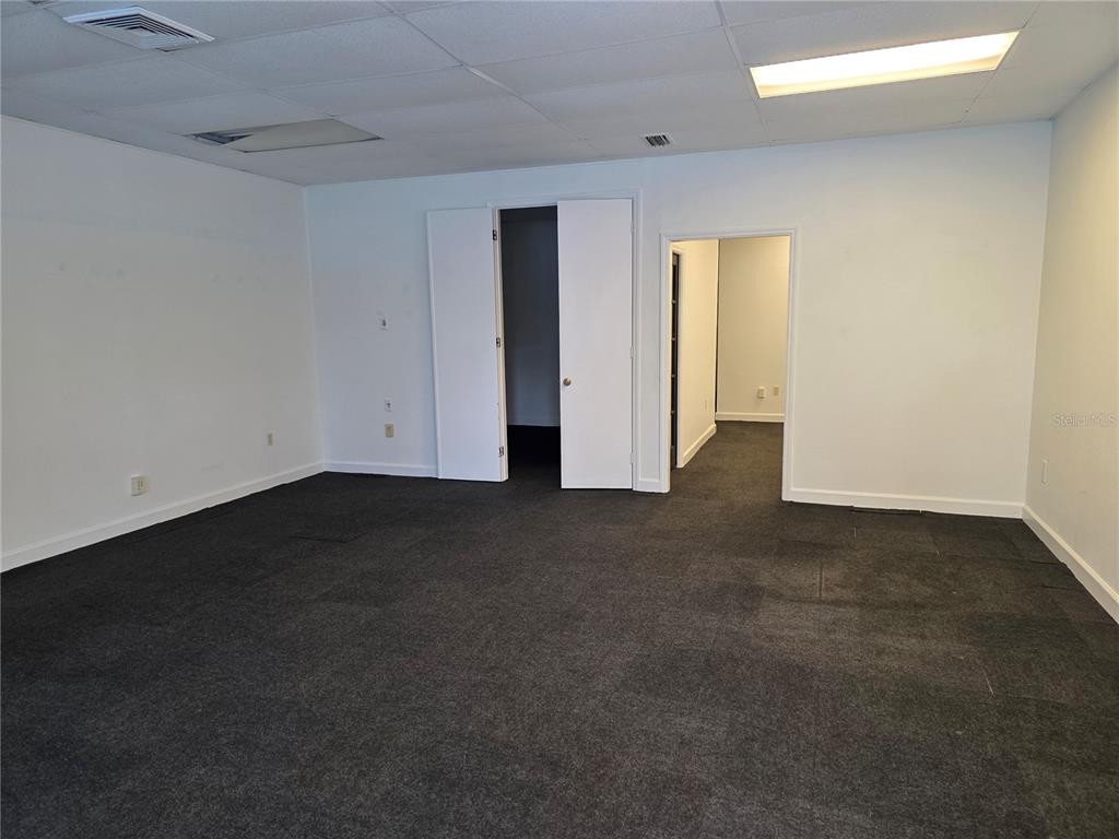 An empty office room features white walls, a dark carpeted floor, and two doorways — 3946 LAKE PADGETT DRIVE, LAND O LAKES, FL