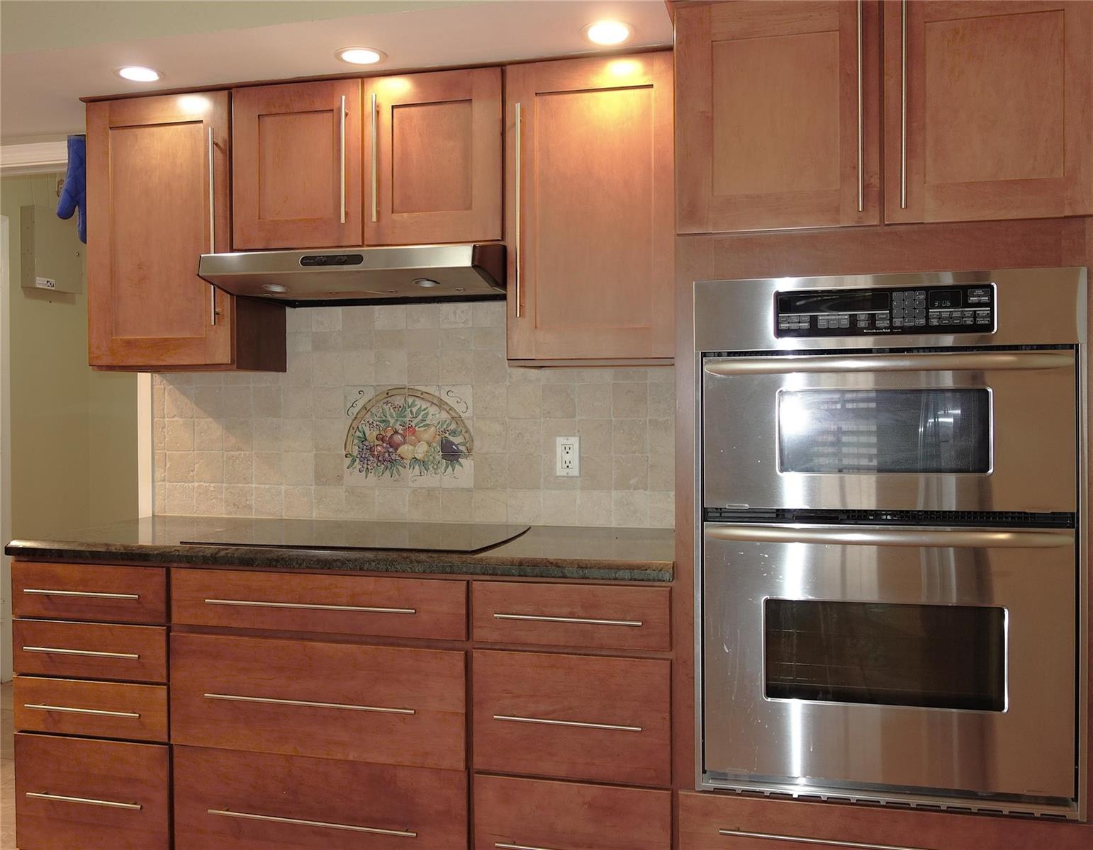 A kitchen features wood cabinets, stainless steel appliances, a tiled backsplash, and dark stone countertops — 4106 Carriage Drive # 5C, Pompano Beach FL 33069, POMPANO BEACH, FL
