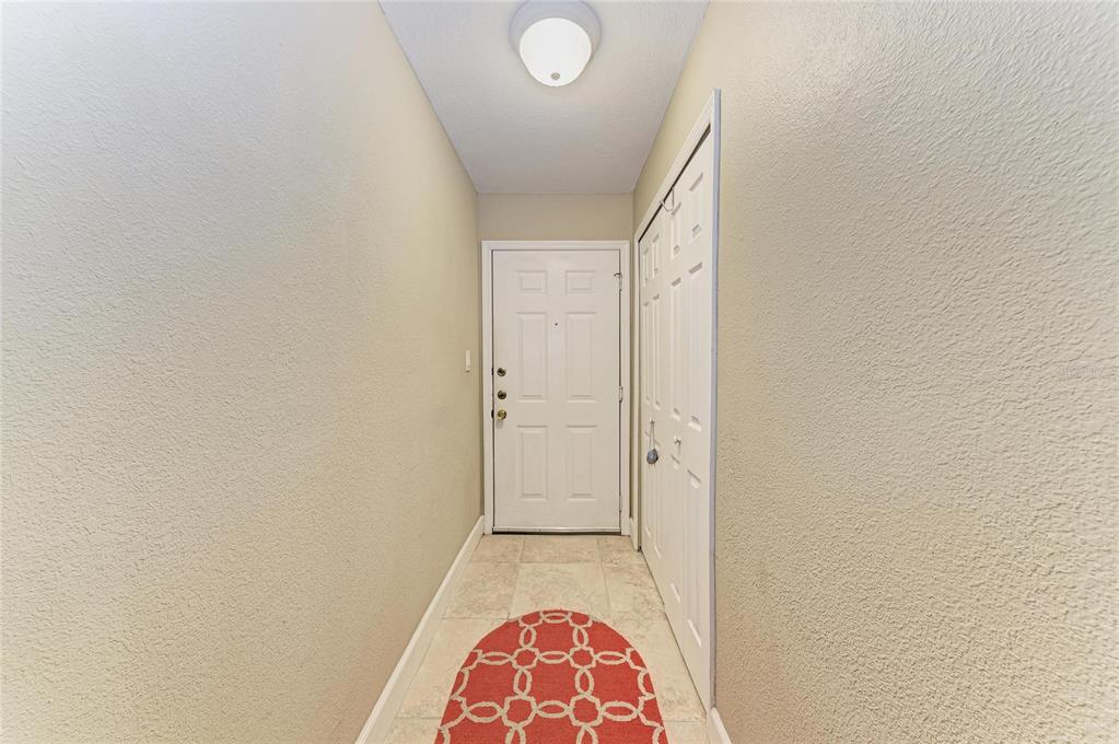 An entryway features a white front door, a closet with bifold doors, and tile flooring — 4040 CROCKERS LAKE BOULEVARD UNIT 12, SARASOTA, FL